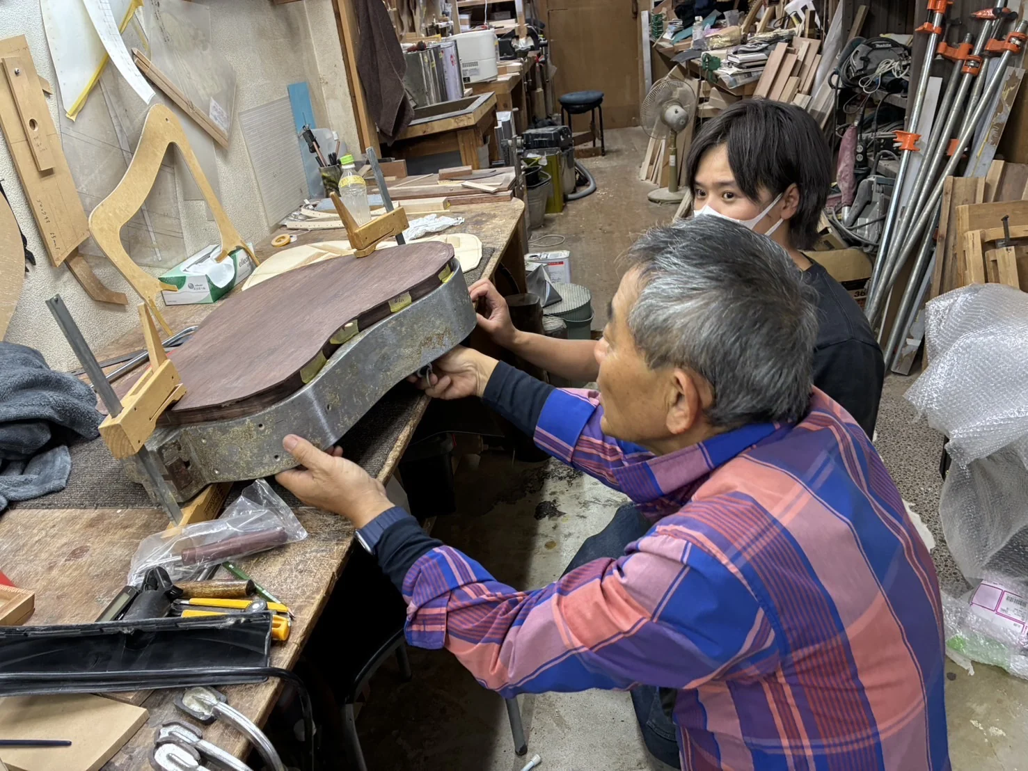 型に収めたギターの胴を、2人で確かめる様子。